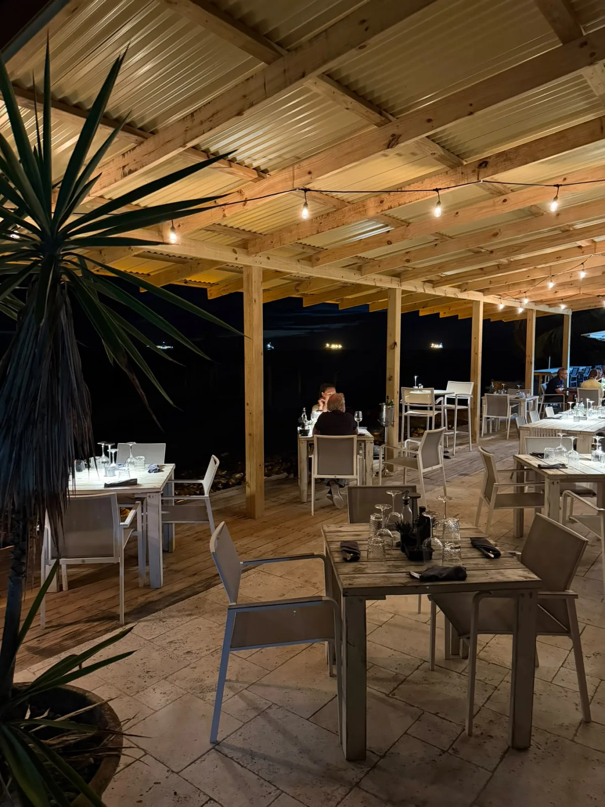 The covered Barrel House waterfront terrace set for dinner at night